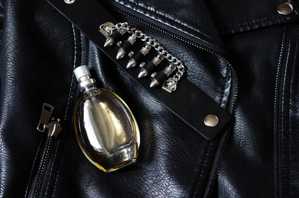 a bottle of women\'s perfume on a black leather jacket. Women\'s perfume and leather bracelet with bullets