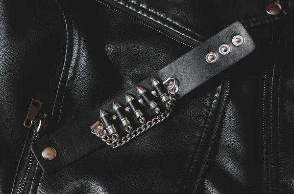 Black leather bracelet with bullets on a leather jacket.