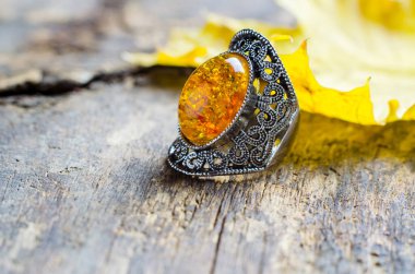 Vintage ring with a large yellow stone on an old wooden background clipart
