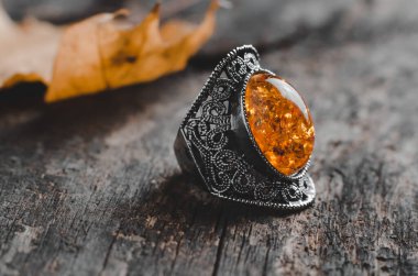 Vintage ring with large orange stone on old wooden background clipart
