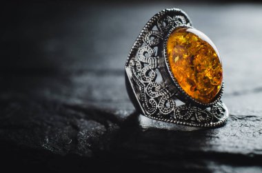 Sarı kehribar taşlı gümüş rengi bir yüzük.