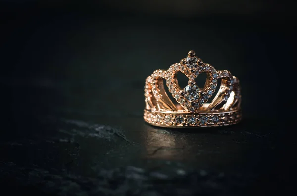 Ring in the form of a crown on a black stone background. Bijouterie products.