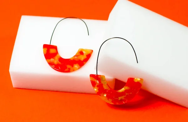 Κομψά κόκκινα-πορτοκαλί σκουλαρίκια σε πορτοκαλί φόντο. Κοσμήματα σε έγχρωμο φόντο — Φωτογραφία Αρχείου