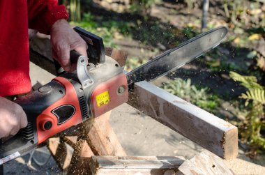 İşçi elektrikli testereyle odun kesiyor..