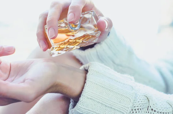 Young woman sprinkles perfume on her wrist. Perfume in a woman's hand