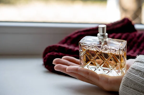 Perfume bottle in a woman\'s palm. Perfume in the palm of your hand