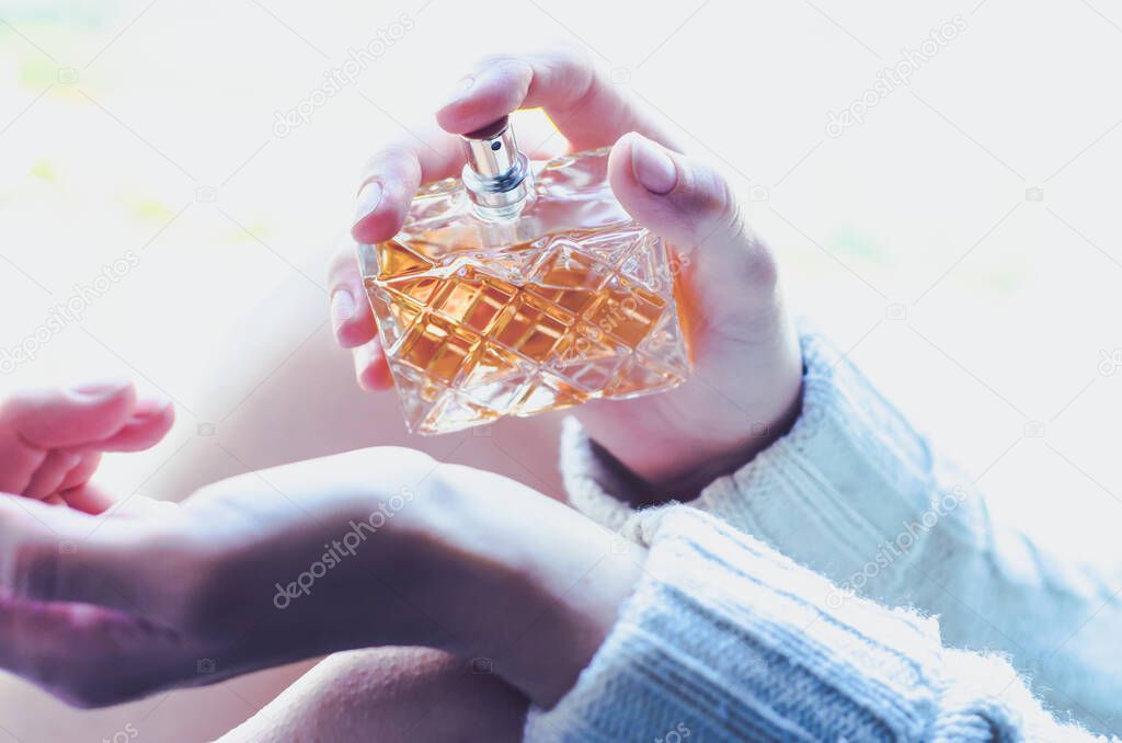 Young woman sprinkles perfume on her wrist. Perfume in a woman's hand