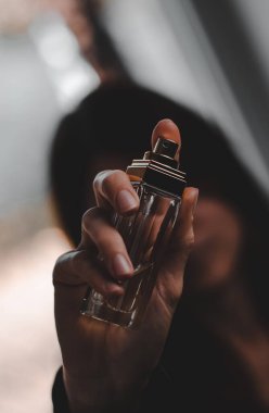 Bir kadın yüzüne bir şişe parfüm tutuyordu.