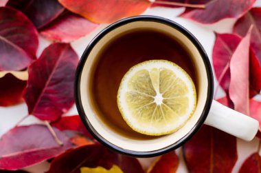 Kırmızı yapraklı, limonlu bir fincan çay..