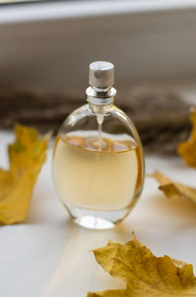 Een Fles Parfum Een Vensterbank Met Gele Herfstbladeren — Stockfoto