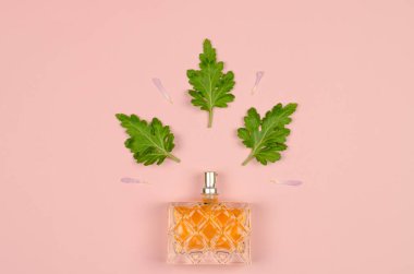 Pembe arka planda çiçek yaprakları ve yaprakları olan kadın parfümü.