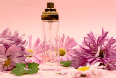 Pembe arka planda kadın parfümü ve çiçekler