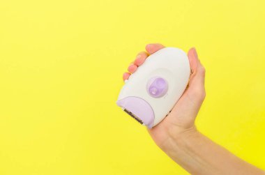 Sarı arkaplandaki bir kadın elinde, mesaj için yeri olan bir epilatör.