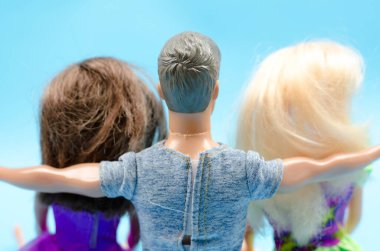 Oyuncak adam iki oyuncak kadına sarılır. Aşk üçgeni