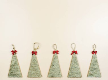 Bej arka planda kırmızı fiyonklu el yapımı Noel ağaçları