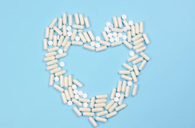 Mavi arka planda kalp şeklinde beyaz haplar.