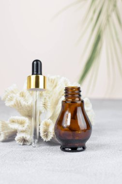 Gerekli yağlar ve kozmetikler için bir şişe. Kahverengi kozmetik şişe, pipet ve ağıl yeşil dallı bej bir arka planda. Doğal organik kozmetik ürünleri..