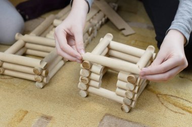 Kız ahşap kütüklerden bir kulübe yapıyor, çocuk ahşap inşaatçısından.