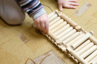 Çocuk odasındaki ahşap inşaatçıyla oynuyor.