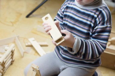 Çocuk ahşap bir inşaat setiyle oynuyor.