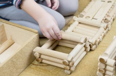 Çocuk ahşap bir inşaat setiyle oynuyor.