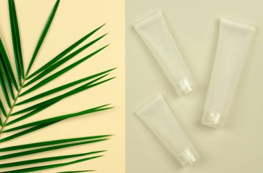 Cilt bakımı için doğal kozmetik ürünleri. Krema için beyaz kozmetik tüp ve bej arka planda yeşil yapraklar, maket