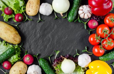 Taze sebzeler ve ayçiçeği fideleri siyah taştan bir arka planda, yazı için yeri var. Sebze arka planı.