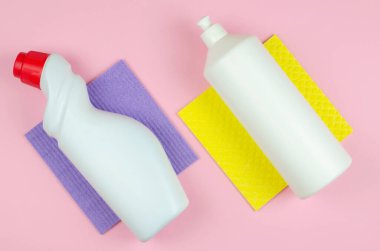 Temizlik aletleri şirket konsepti. Deterjanlı beyaz şişeler, temizlik ürünleri ve renkli arka planda bir sünger. Pembe arka planda temizlik ürünleri.