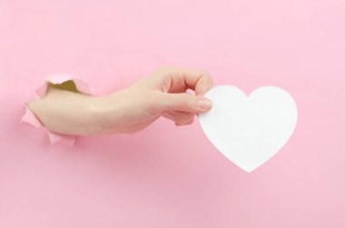 Bir kadının elinde, beyaz kağıttan kesilmiş bir kalp. Metin için yeri olan kağıt kalp