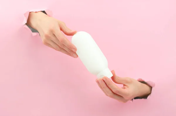 Kadın eli, krema veya yağ için beyaz bir tüp tutar. Güzellik uzmanlığı konsepti. Logo için uzayı kopyala. Krem veya losyon için plastik şişe. Cilt bakımı ve güzellik konsepti. Mockup, boşluğu kopyala