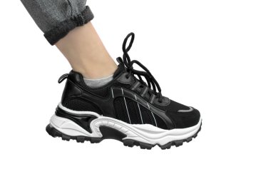 Ayakkabılı kadın ayak, izole et. Beyaz arka planda siyah beyaz spor ayakkabılı güzel kadın bacağı.