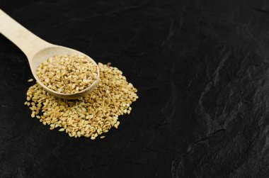 Tahta bir kaşıkta keten tohumu siyah bir taş zemin üzerinde