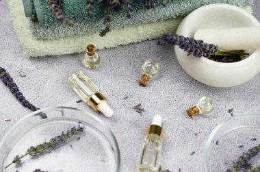 Lavanta yağı, lavanta çiçeği, havan topu, tokmak ve petri kabı içeren şişelerin bileşimi. Doğal kozmetik konsepti, seçici odaklanma