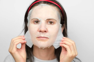 Kadın yüzüne nemlendirici bir maske takıyor. Cilt bakımı kavramı