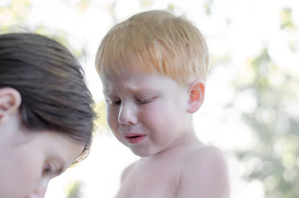 A 4-year-old boy cries while his mother pulls out a splinter. Redhead little boy crying