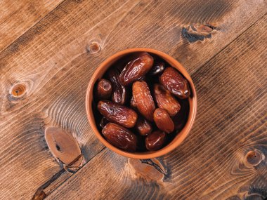 Kaba ahşap arka planda kahverengi bir seramik kasede tarihler.