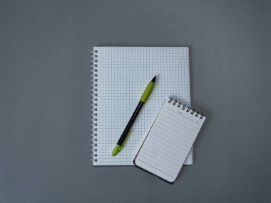 Gri arkaplanda işaretlenmiş defterler ve kalemler