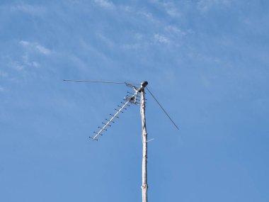 Eski bir televizyon anteni ahşap bir direğe bağlanmış bulutların arkasına..