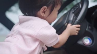 Araba şoförü koltuğunda oturan tatlı Asyalı kız çocuğu direksiyon simidi, çocukluk anısı ve merakı, mutlu ve neşeli çocuk öğrenme becerisi, saf ve masum kız, çocuklukta öğrenme yeteneği, masumiyet ve merak.