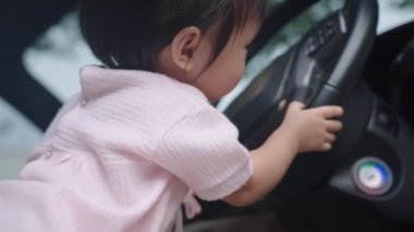 Araba şoförü koltuğunda oturan tatlı Asyalı kız çocuğu direksiyon simidi, çocukluk anısı ve merakı, mutlu ve neşeli çocuk öğrenme becerisi, saf ve masum kız, çocuklukta öğrenme yeteneği, masumiyet ve merak.