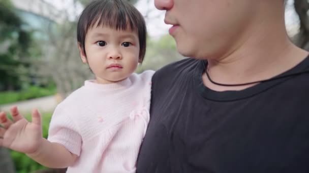 アジアの若い父親は 彼の腕の中で彼の可愛い赤ちゃんの娘を保持し 家族の暖かさは 公園で一緒に時間を過ごす 幼児の若い年齢開発 週末に家族の活動は 屋外で散歩を取り 子供と責任を高める 学習能力 — ストック動画