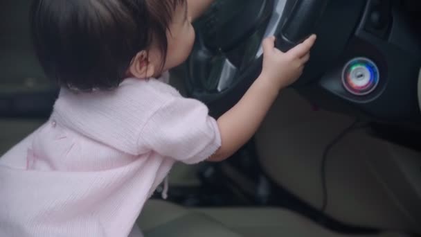 亚洲女孩不知道在车里玩耍 孩子们学习技能 玩方向盘的汽车 坐在汽车司机座位上的婴儿 快乐的女婴假装是司机 童年的学习能力 家庭的柔情 — 图库视频影像