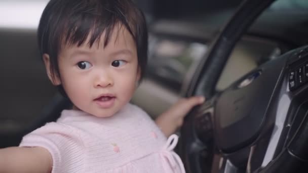 子供の発達学習能力 ステアリングホイールで遊んで車の中で楽しい時間を過ごして 車の運転席に座って赤ちゃん 幸せな幼児の女の子は彼女自身を運転するふりを楽しんで 子供の頃の学習能力 無実の好奇心 — ストック動画