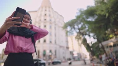 Tesettürlü genç Asyalı Müslüman kadın turist arka plan, yaşam tarzı ve seyahatte kendi kendine selfie çekiyor, zaman çizelgesini paylaşıyor, mutlu ve neşeli kız, kablosuz internet bağlantısı, modern din hayatı