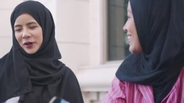 İki genç Müslüman kadın öğleden sonra kahve molasında tesettür takıyor, kız kıza sohbet ediyor, kafede dinleniyor, İslami kültürü sosyalleştiriyor, arkadaşlığın tadını çıkarıyor.