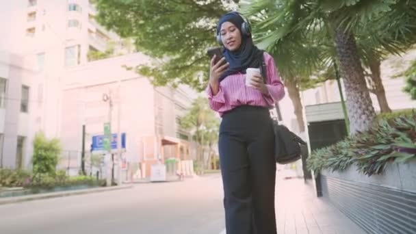 Ung Asiatisk Muslim Bära Hörlurar Lyssna Musik Hålla Kaffekopp Stående — Stockvideo