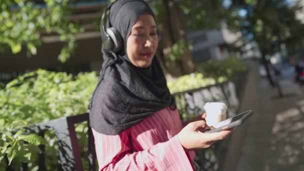 Młody Południowo Wschodni Azjatycki Muzułmanin Nosić Słuchawki Słuchać Muzyki Trzymając — Wideo stockowe
