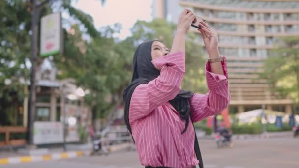 アジアのイスラム教徒の少女は 市内観光 写真メッセージを送信する人々を接続する近代的な技術の写真を撮るスマートフォンを使用してヒジャーブを身に着けているインターネットアクセス 電話カメラの解像度 近代的な技術とライフイベントの思い出 — ストック動画