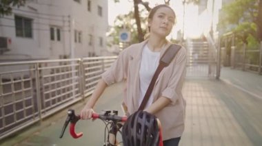 Güneşli bir günde parkta bisikletle yürüyen ve gülümseyen çekici sarışın bir kadının portresi. Yazın açık havada, doğa ve güzellikte, kentsel yaşam tarzında, çevresel koruma veya diğer konulardaki mutlu güzel kadının yüzü, masraflardan tasarruf.