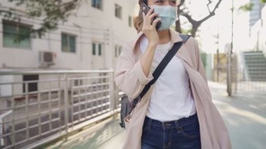 Yeşil parktaki üst geçitte yürürken telefonla konuşan aktif genç işçilerin portresi, teknoloji kablosuz ve modern yaşam tarzı, yeni normal yaşam tarzı, çevresel koruma veya sorunlar, yeşil enerji,